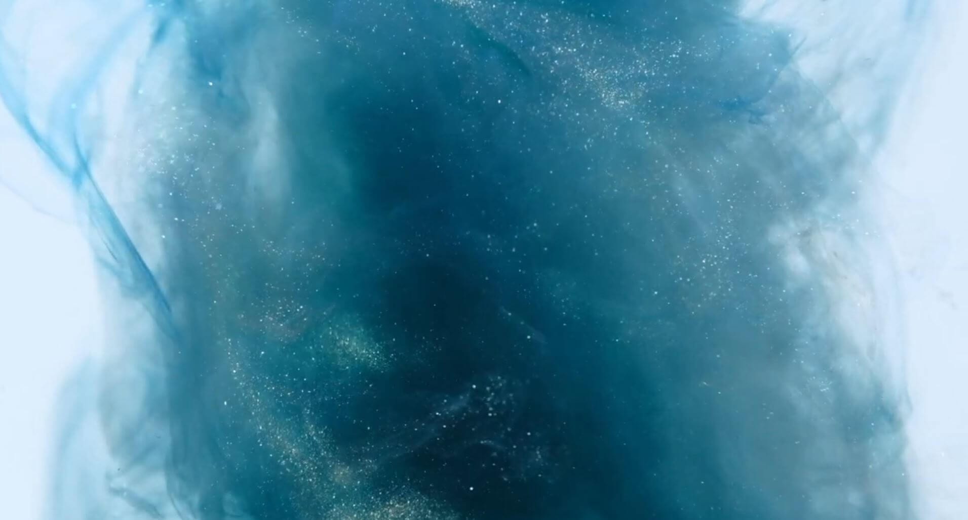 Blauer Rauch mit glitzernden Partikeln, die im hellen Licht schweben. Mystische und künstlerische Atmosphäre.