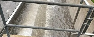 Abwasserbehandlungsanlage mit Wasserkanälen in grüner Umgebung.
